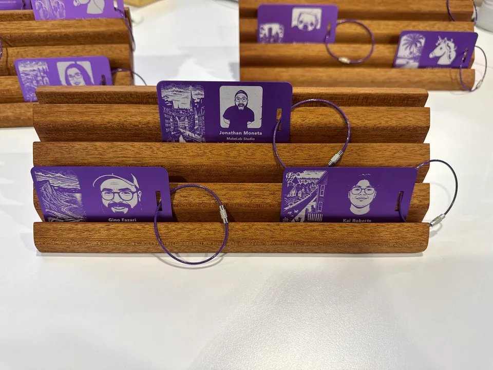 A timber rack of illustrated purple name tags, each with a portrait and a lanyard loop.