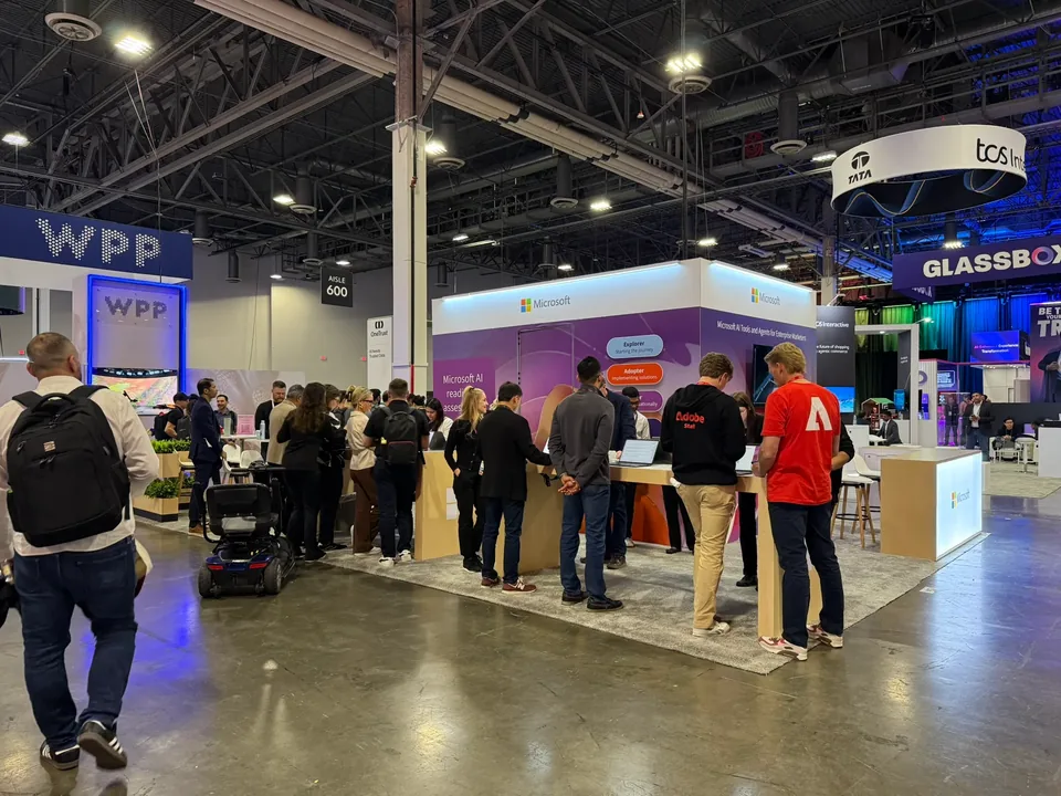 A line of attendees along the demo counter, staff in red Adobe shirts working among them.