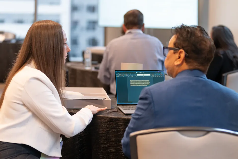 Attendees working on a laptop together during a session.