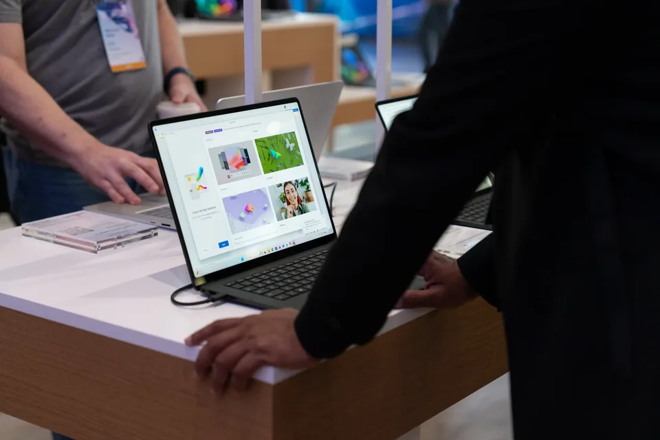 Hands on a Surface laptop at a timber demo counter, a second device open beside it.
